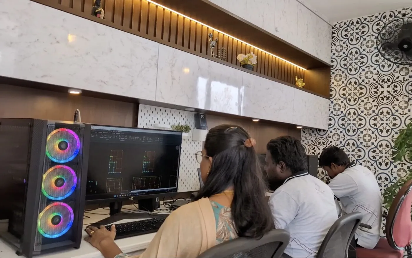 Poriyaalan's design team at work in the studio — an architect reviewing a structural CAD drawing on screen while colleagues collaborate